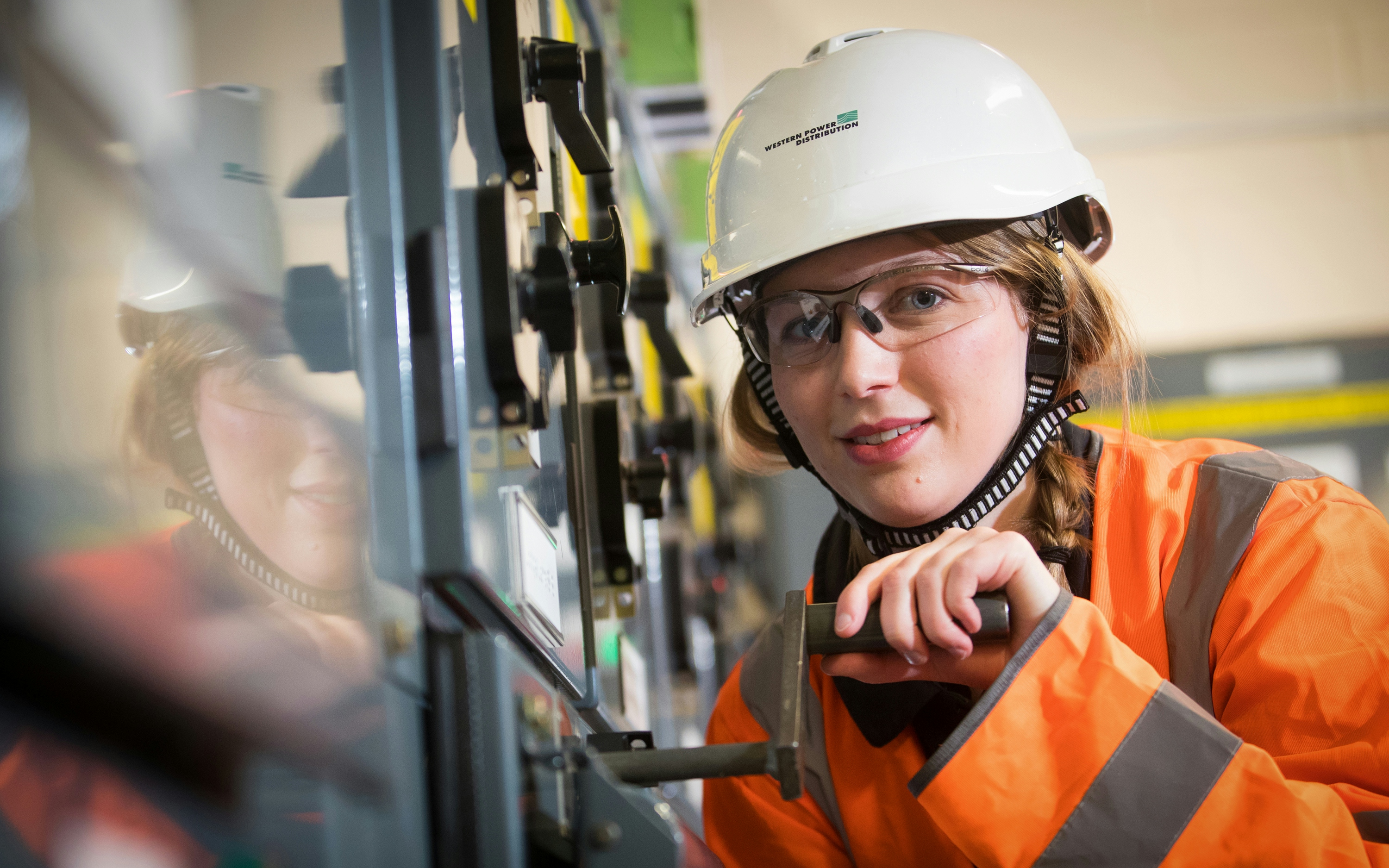 A woman with a hard hat working in an industrial setting